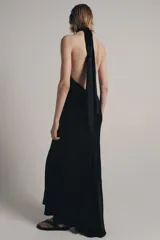 Vestido largo de satén negro con cuello halter subido y espalda descubierta. Presenta un diseño fluido con bajo en línea evasé.