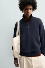 Sudadera de corte relajado confeccionada en tejido de algodón. Presenta cuello subido con cierre frontal de cremallera metálica, manga larga y acabados en rib en puños y bajo.