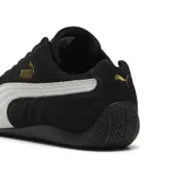 Championes Puma Speedcat OG de gamuza negra con franja lateral blanca, logo de Puma dorado en el lateral y logo de automovilismo en la puntera.
