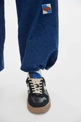 Sneaker Club 82 de cuero, color negro con detalles en beige y suela marrón. Cuenta con cordones off-white y una altura de suela de 3 cm.