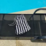 Short de baño con rayas verticales en verde y negro, con cintura elástica ajustable con cordón y logo estampado en la pierna.