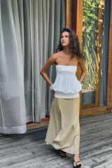 Vestido midi de diseño strapless con escote recto. Presenta un cuerpo superior blanco con textura fruncida y una falda inferior en tono beige con caída fluida.