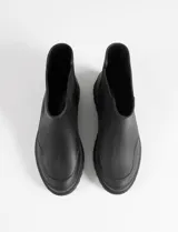 Botas de lluvia tipo chelsea de goma opaca color negro, con paneles laterales elásticos y suela track dentada.