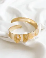 Brazalete rígido dorado con cuatro piedras de citrino en bruto engarzadas en la parte frontal.