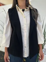 Chaleco negro de corte sastrero, con solapas amplias y diseño abierto sin botones.