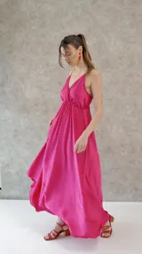 Vestido solera largo de seda color fucsia, con escote en V pronunciado en el frente y la espalda, y cintura elastizada.