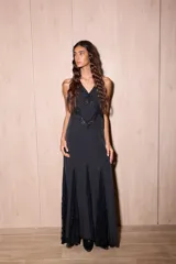 Vestido largo de seda color negro con estampado de lunares blancos. Presenta una silueta fluida, escote en V profundo con detalles de encaje y espalda descubierta con tiras cruzadas.