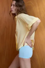 Camisa de corte fluido con cuello solapa y manga corta con dobladillo. Presenta cierre frontal con botones ocultos bajo una tapeta.