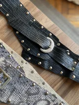 Cinto de cuero con hebilla metálica y diseño texturizado símil piel de cocodrilo, serpiente o charol.