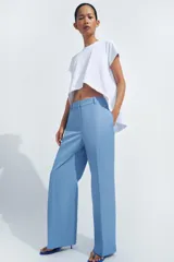 Pantalón de tiro medio con corte recto, confeccionado en mezcla de algodón. Presenta cintura con trabillas, bolsillos laterales ocultos en costura, raya planchada en el delantero y cierre frontal con cremallera, botón y ganchos metálicos.