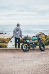 Hoodie de corte oversize color gris con efecto lavado. Presenta una estampa en la espalda con diseño de palmeras, flores y el texto 'Glassy Waves Club'.