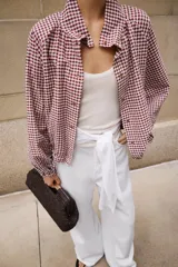Chaqueta de manga larga con estampado de cuadros vichy en tonos marrón y blanco, cuello camisero, cierre frontal con botones y bajo ajustable con cordón.