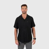 Camisa de manga corta en color negro con estampado sutil de motivos tropicales, cuello tipo cubano y cierre frontal con botones. Presenta un bolsillo en el pecho con etiqueta de marca.