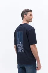 Remera de manga corta color azul marino con cuello redondo y calce regular. Presenta un estampado artístico en la espalda con diseño floral estilizado y tipografía.