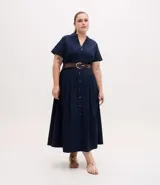 Vestido chemise midi de corte holgado, confeccionado en tricolina color azul marino. Presenta cuello tipo padre, cierre frontal con botones metalizados, mangas cortas y pliegues en la falda. Incluye un cinturón marrón para ajustar a la cintura.