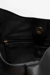Cartera tipo hobo de diseño slouchy en color negro, confeccionada en material texturizado. Presenta una correa de hombro ajustable y un detalle de tira fina frontal con cierre de mosquetón metálico dorado que frunce el centro de la pieza. Cuenta con cierre magnético oculto y forro interior.