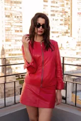 Chaqueta de cuero ovino color rojo, con cierre frontal de metal, cuello redondo y mangas largas con puños anchos ajustables mediante broches metálicos.