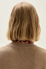 Sweater de punto color beige, con cuello redondo, manga larga y puños acanalados.