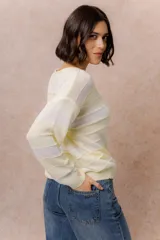 Buzo de tejido liviano con diseño de rayas horizontales en tonos amarillo manteca y blanco, cuello redondo y mangas largas con puños tejidos.