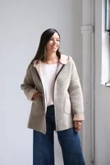 Tapado de paño con capucha, color beige, con cierre frontal, bolsillos laterales y puños vueltos en tono más claro.
