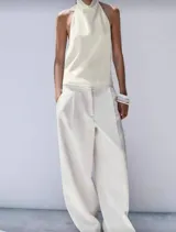 Blusa color blanco hueso de seda con escote halter, espalda descubierta y cierre con botones ocultos.