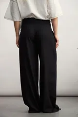 Pantalón de corte sastrero y tiro alto, con diseño de pierna ancha y pinzas frontales. Cuenta con bolsillos laterales y cierre frontal con botón oculto.