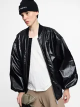 Chaqueta negra con cierre frontal, cuello redondo y mangas globo.