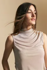 Top sin mangas de color negro con cuello alto y diseño drapeado en el frente. Confeccionado en una tela suave con acabado levemente satinado y silueta fluida.