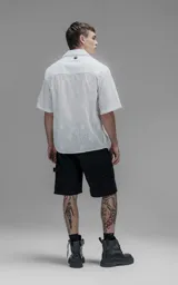 Camisa oversize blanca de manga corta y cuello abierto, confeccionada en algodón con diseño bordado.