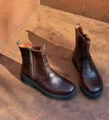 Botas de cuero con textura simil cocodrilo en color marrón, diseño de caña baja con cierre lateral y suela track negra de goma.