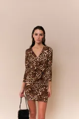 Vestido corto ajustado al cuerpo, con estampado animal print, escote en V, mangas largas y volados frontales.