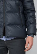 Campera puffer verde militar con capucha negra de cuero sintético, cierre frontal con cremallera y bolsillos laterales con cierre.