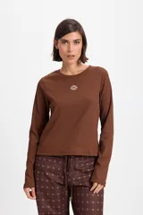 Remera de manga larga con textura acanalada y silueta ajustada. Presenta cuello redondo y un pequeño bordado decorativo en el centro del pecho.