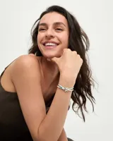 Pulsera de diseño náutico con hilo de seda color turquesa, intercalado con cuentas metálicas plateadas y cristales facetados en tono azul. Presenta un dije central en forma de estrella de mar plateada y cierre de mosquetón con placa de marca.