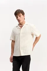 Camisa de manga corta color beige con tejido calado de líneas verticales y cuello abierto estilo resort.