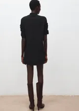 Vestido corto de punto en color negro, con cuello alto y manga larga. Presenta un diseño minimalista y ajustado.