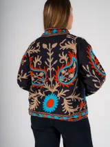 Chaqueta corta negra con bordados florales en tonos naranja, celeste y beige.