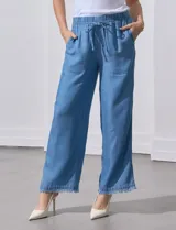 Pantalón celeste de lyocell, corte ancho, con pretina elastizada con lazo de ajuste, bolsillos verticales y ruedo desflecado.