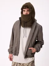 Pasamontañas de tejido tipo corderito sintético en color negro, con diseño de capucha integrada y cordones ajustables en la parte frontal.