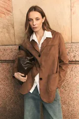 Blazer de gamuza sintética color camel, con cierre frontal de tres botones, solapas clásicas y dos bolsillos frontales de parche.