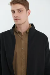 Cardigan de tejido de punto color verde militar, con cierre frontal de metal y cuello redondo. Presenta detalle de tejido plano en la cartera del cierre y en los bolsillos laterales.