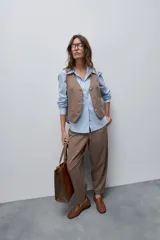 Pantalón marrón de tiro alto y silueta amplia, confeccionado con pinzas en el frente y bolsillos laterales.