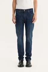 Pantalón de jean azul oscuro, corte slim fit, tiro medio y confección sin elasticidad.