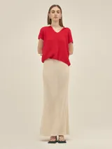 Top tejido color crema, de manga corta, con cuello polo azul marino y corte holgado.