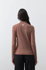 Polera de cuello alto con diseño de rayas horizontales en color azul marino sobre fondo blanco, confeccionada en tejido de punto con mangas largas.