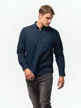 Camisa de franela color azul marino, de manga larga, con cuello abotonado, un bolsillo frontal y cierre de botones.
