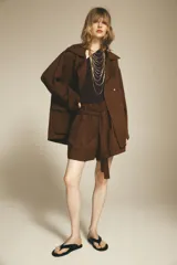 Trench color marrón confeccionado en mezcla de lyocell y lino. Cuello solapa y manga larga. Bolsillos con solapa en delantero. Cierre frontal con botones a presión.