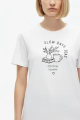 Remera de manga corta de algodón, color blanco, con cuello redondo y estampado frontal estilo collage con gráficos y texto en tono bordó.