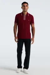 Chomba de piqué color bordó con detalles de ribetes blancos en cuello y mangas. Presenta cierre frontal de tres botones y logo de pingüino bordado en el pecho.