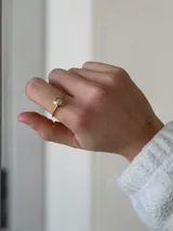 Anillo de acero quirúrgico dorado con diseño de flor y piedra central brillante.
